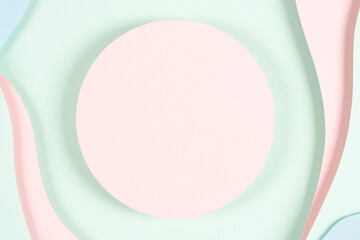 Blank pink round geometric shape podium platform on paper cut abstract geometric shape pastel pink, blue and green background. Top view mock up for product display