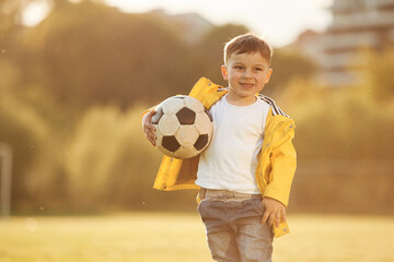 Boy is on the summer field with soccer ball
