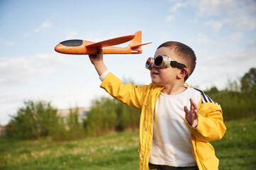Little boy is playing with toy plane on the summer field © standret