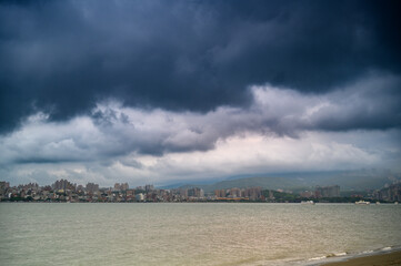 On cloudy days, there are fast moving clouds over the Tamsui River. The buildings overlooking Tamsui from the left bank of Bali, New Taipei City.
