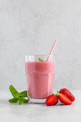 Strawberry smoothie in a glass with straw, fresh berries and mint. Summer refreshing drink. Healthy...