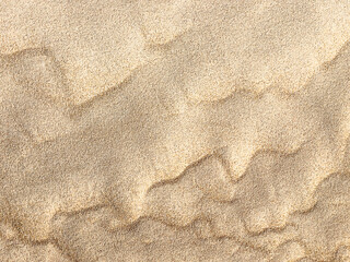 Sand. Texture, surface of sea sand. Natural background. Close-up. Waves of sand. Dunes. Copy space
