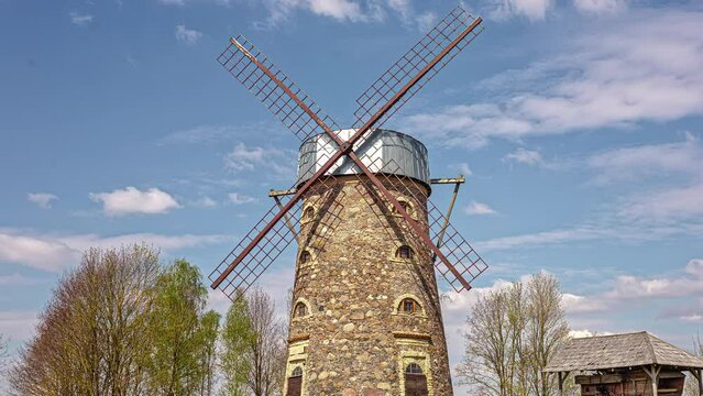 Timelapse of old stone windmill with clouds in blue sky