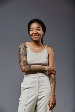 Vertical portrait of confident black woman with tattoos looking at camera and smiling