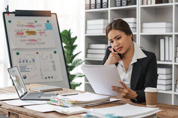 business woman sitting at office desk in front of laptop hold mobile phone make pleasant business or informal call. Successful businessman looking at financial statistic shown on documents