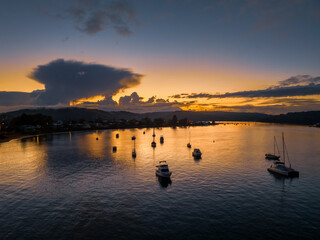 Aerial sunrise waterscape with scattered rain clouds, fog and boats