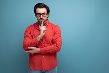 Fototapeta na wymiar smart handsome young brunette man in glasses and a red shirt on the background with copy space