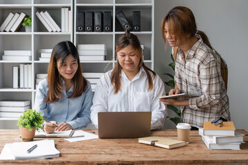 Laughing students use laptop studying or having fun using laptop sit at shared table in university library, having friendly relations, prepare for exams together using modern tech concept