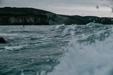 Wave in the ocean against a hilly backdrop