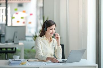 Portrait of happy smiling female customer support phone operator at workplace. Asian