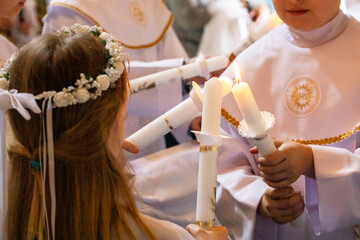 children distribute fire from candles of peace candles to other candles at first communion