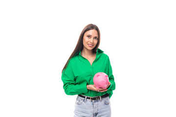 brown-eyed brunette young business lady in a green shirt holds a piggy bank with money