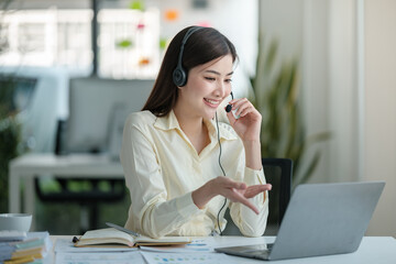 Portrait of happy smiling female customer support phone operator at workplace. Asian