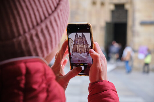 Tourist woman traveling St. Vitus Cathedral takes a photo in Prague with her mobile phone
