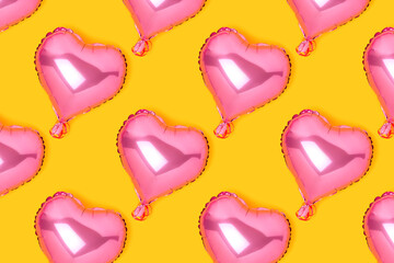 Repetitive pattern made of pink inflatable foil balloons in a heart shape. Festive concept on a...