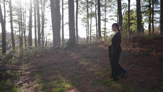 黒いドレスを着た日本人女性が森林の中を歩いている風景のスローモーション映像 Slow motion video of a Japanese woman in a black dress walking through a forest landscape 4K60fps