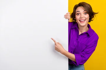 Gardinen Portrait of cheerful person direct finger empty space billboard proposition isolated on yellow color background © deagreez