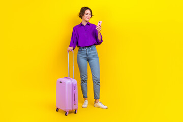 Full length photo of positive pretty lady wear violet shirt online booking journey modern device isolated yellow color background