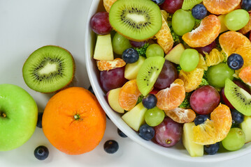 Healthy fresh fruit salad bowl on white background. Top view. Healthy food concept, healthy high vitamin fruit, mixed fruit background.
