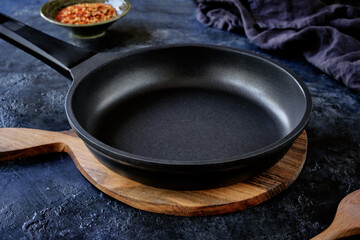 Close-up of an empty black non-stick frying pan on a beautiful dark background.