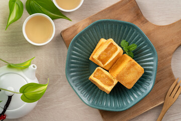 Delicious pineapple cake pastry in a plate on wooden table background with tea.
