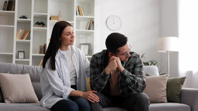 A sympathetic young woman provides psychological support to a thoughtful upset loved one in a difficult life situation, showing loving care, overcoming grief together, or apologizing indoors.