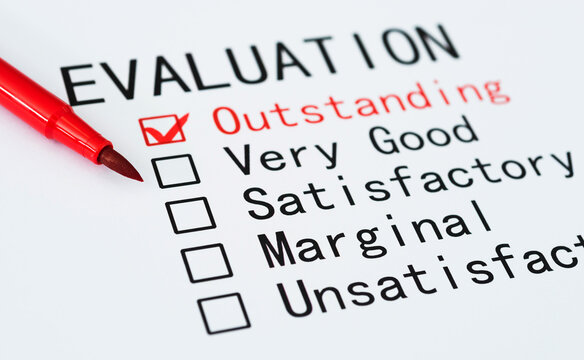 Pen checking the word Outstanding in a evaluation