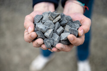 Gravel in the hands of a quarry worker. Worker holding pebbles in hands. Crushed stone quarry in...