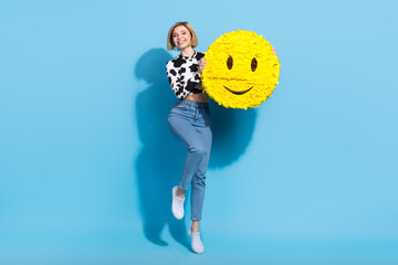 Full size photo of excited charming girl jumping hands hold large smiley emoji collage isolated on blue color background