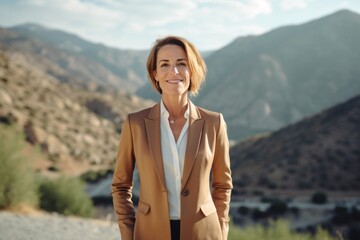 Naklejka premium Lifestyle portrait photography of a glad mature woman wearing a sleek suit against a scenic mountain trail background. With generative AI technology