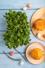 Homemade cakes with chocolate eggs and borage microgreen on a blue, top view, close up.