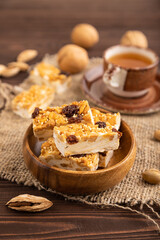 Traditional candy nougat with nuts and sesame on brown wooden, side view, selective focus.