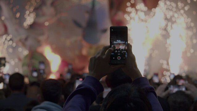 Fallas on the streets of Valencia, Spain. People capturing the burning of ninot dolls on their mobile phones