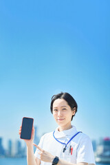 スマートフォンを手にする白衣の女性