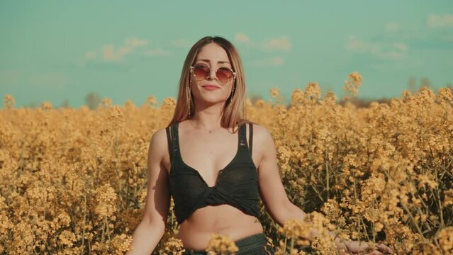 Beautiful sexy young woman on yellow flower meadow in sunset