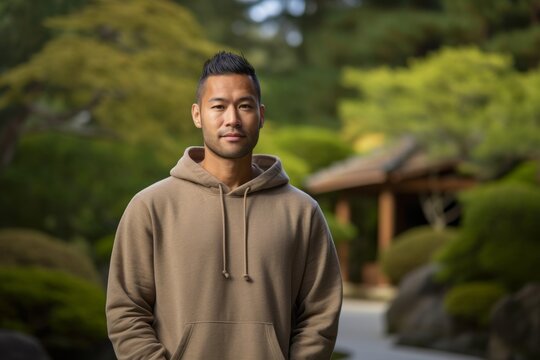Environmental portrait photography of a satisfied boy in his 30s wearing a stylish hoodie against a tranquil japanese garden background. With generative AI technology