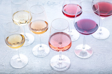 Wine glasses at a tasting. Rose, red, and white wine, drinks on a table at a winery. An assortment of wines of many different colors