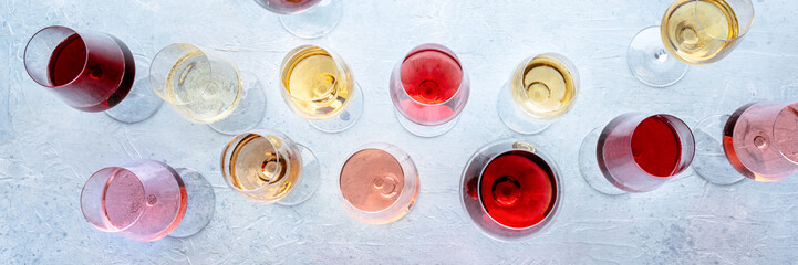 Wine glasses at a tasting panorama. Rose, red, and white wine, drinks, overhead flat lay shot. An assortment of wines of many different colors panoramic banner