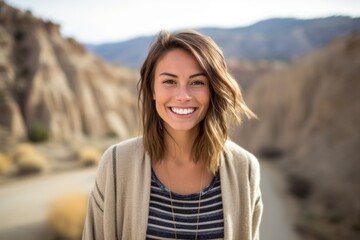 Lifestyle portrait photography of a grinning girl in her 30s wearing a chic cardigan against a scenic canyon background. With generative AI technology
