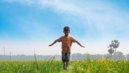 A child dances with nature on a rural path. Children in the village of Bangladesh play in the field.