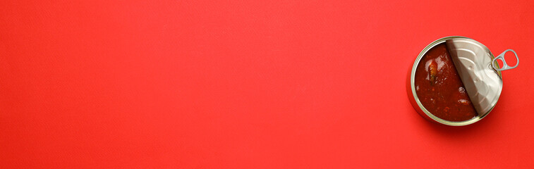Canned fish in tomato on red background