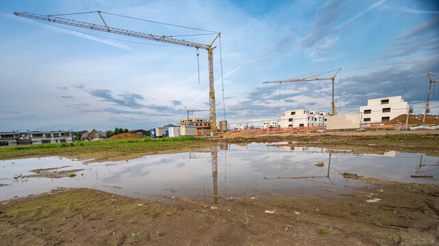 Neubaugebiet mit H&auml;usern und Baumaschinen und Spiegelung