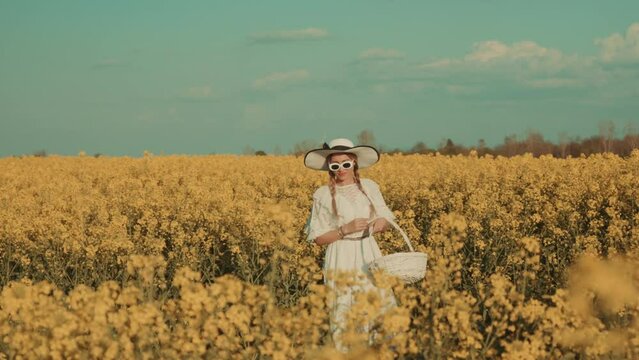 Beautiful young woman in white dress on yellow flower meadow in sunset