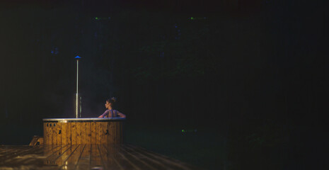 Young woman chill in hot tub SPA at the nature in the night time. Copy space image.