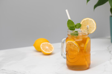 A glass of cold tea, ice cubes, lemon slices and a sprig of mint. Cooling summer drinks.