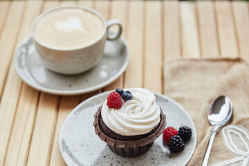 French cupcake with cup of coffee outside. Aesthetic cotton decoration. Cozy breakfast