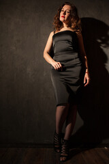 a woman in a black dress stands in a dark room
