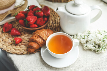 Cup of tea, croissant, strawberry and lilac basket, summer morning aesthetic
