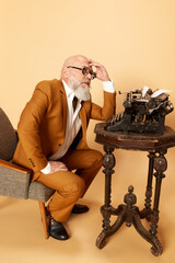 Portrait of thoughtful, bearded, mature, bald man in elegant, classical suit sitting near...