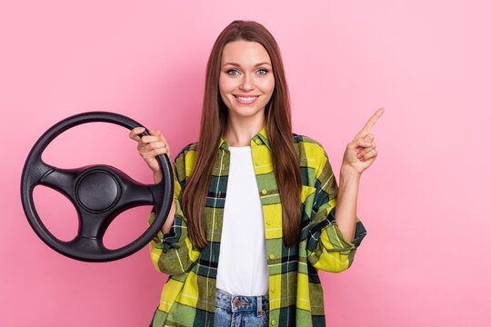 Photo of young beautiful woman wear checkered jacket steering wheel direct finger mockup car safety insurance isolated on pink color background